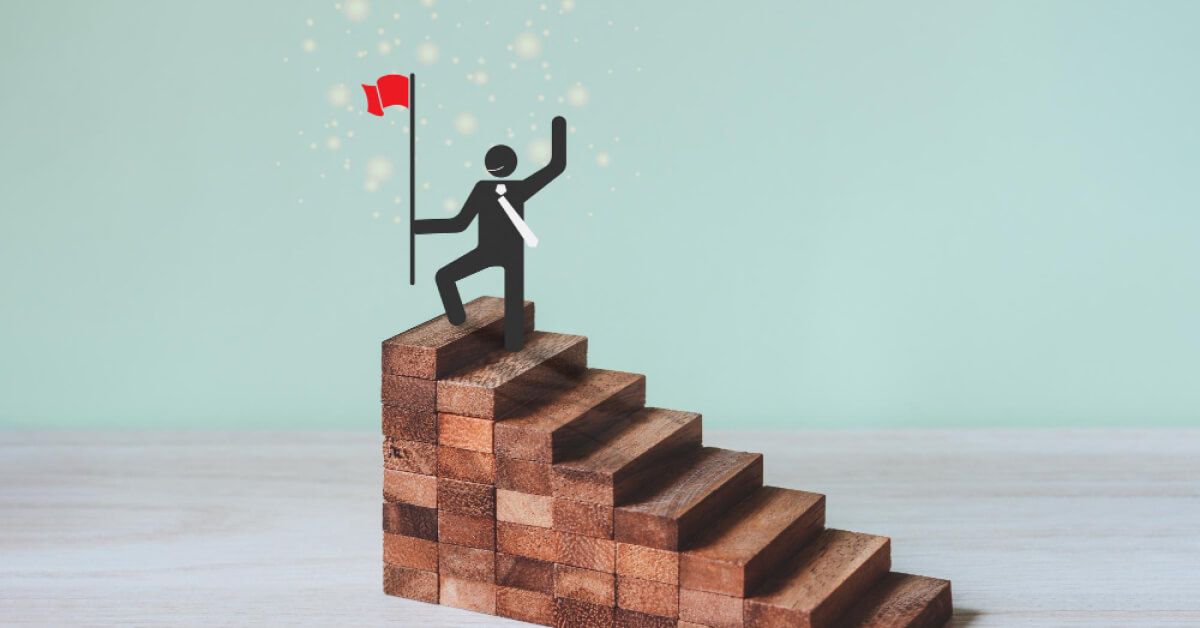 Graphic of a person achieving victory at the top of a series of wooden blocks that are arranged like steps