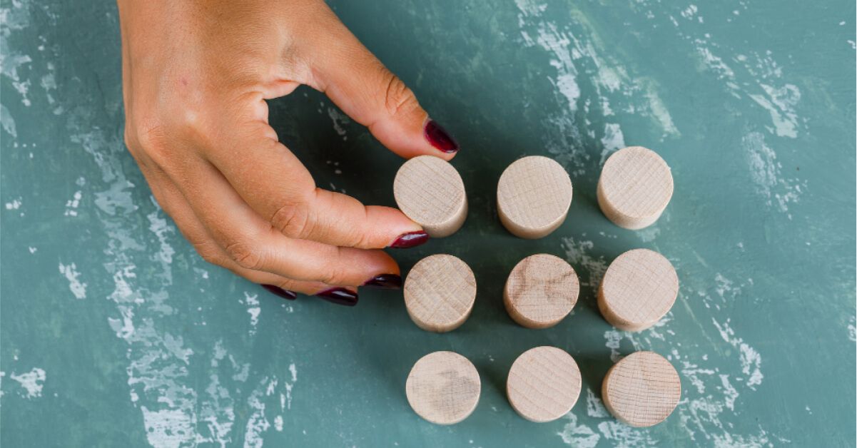 Person placing a wooden block into a grid of other wooden blocks