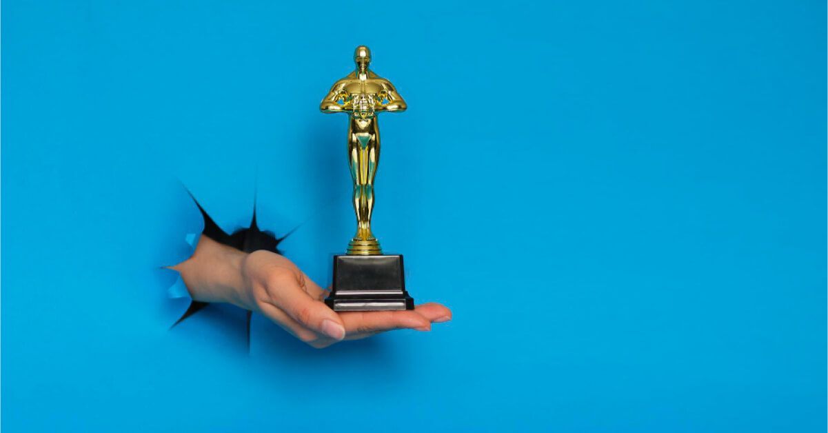 Person breaking through a blue barrier with an award in hand