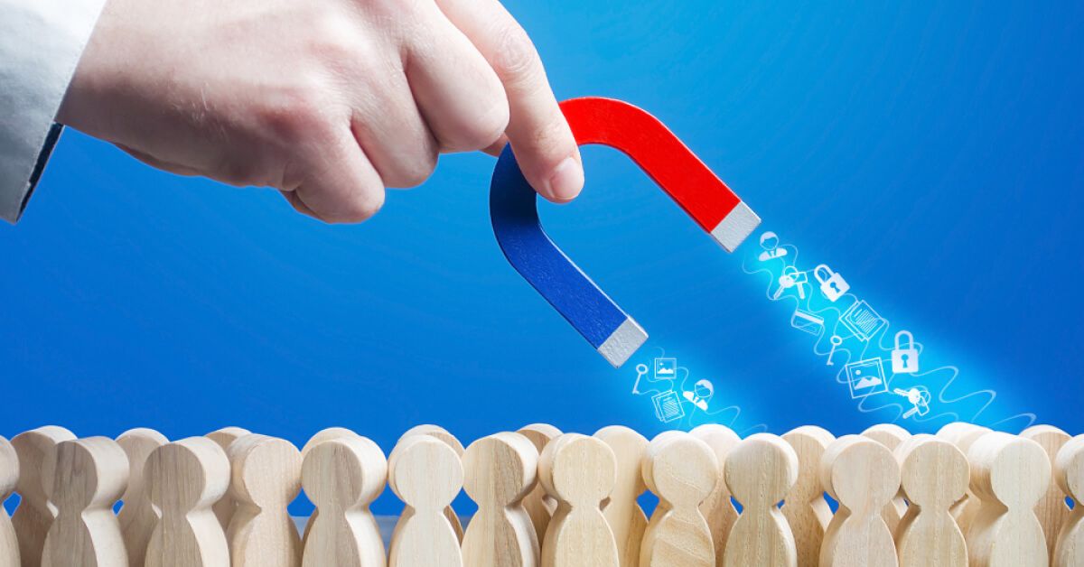Someone holding a horseshoe magnet over a group of wooden pawns