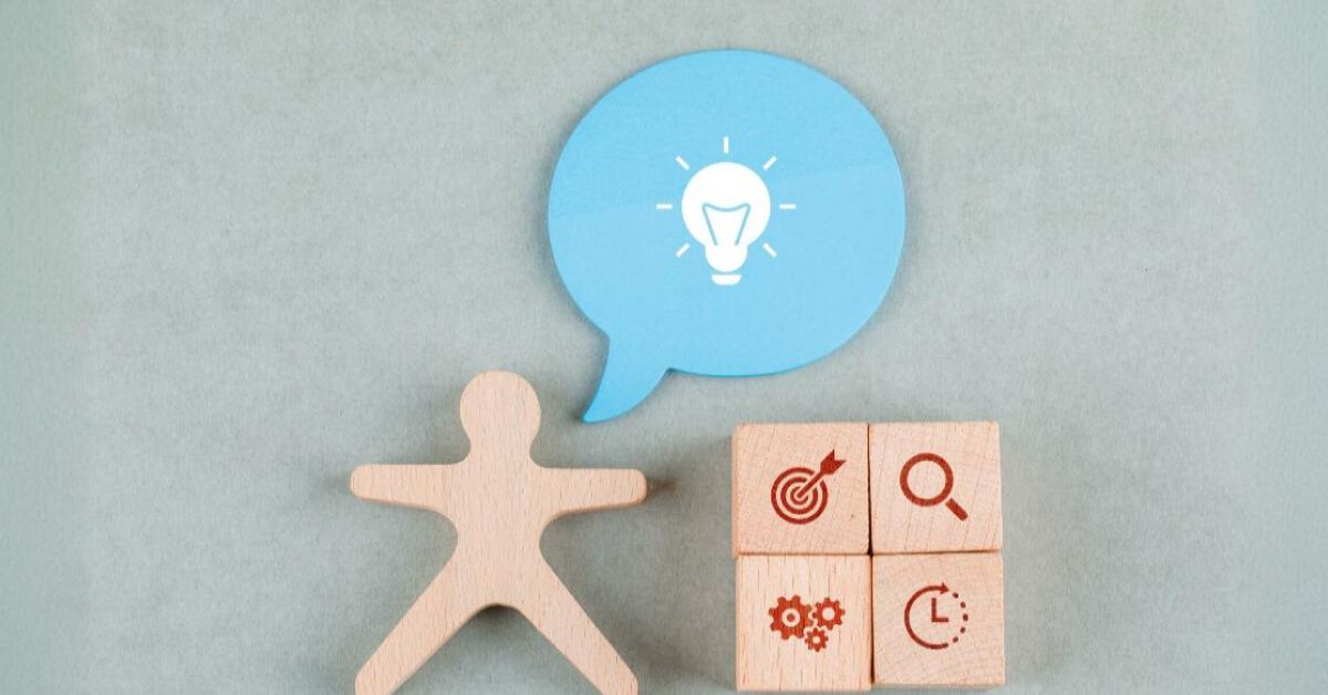 Wooden figurine next to wooden blocks with graphics and a blue speech box