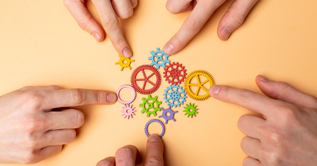 People joining variably coloured and sized gears together