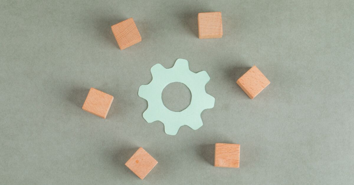 Wooden blocks arranged around a paper cutout of a gear