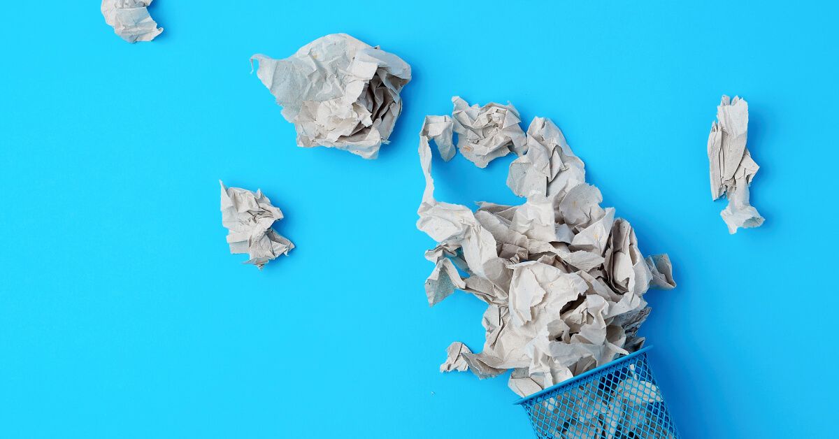 Torn and crushed paper flowing out of a blue bin