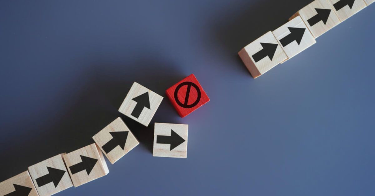 A red block stopping continuity of a series of wooden blocks with arrows