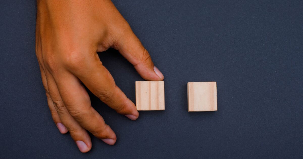 Hand placing two cube wooden blocks to each other