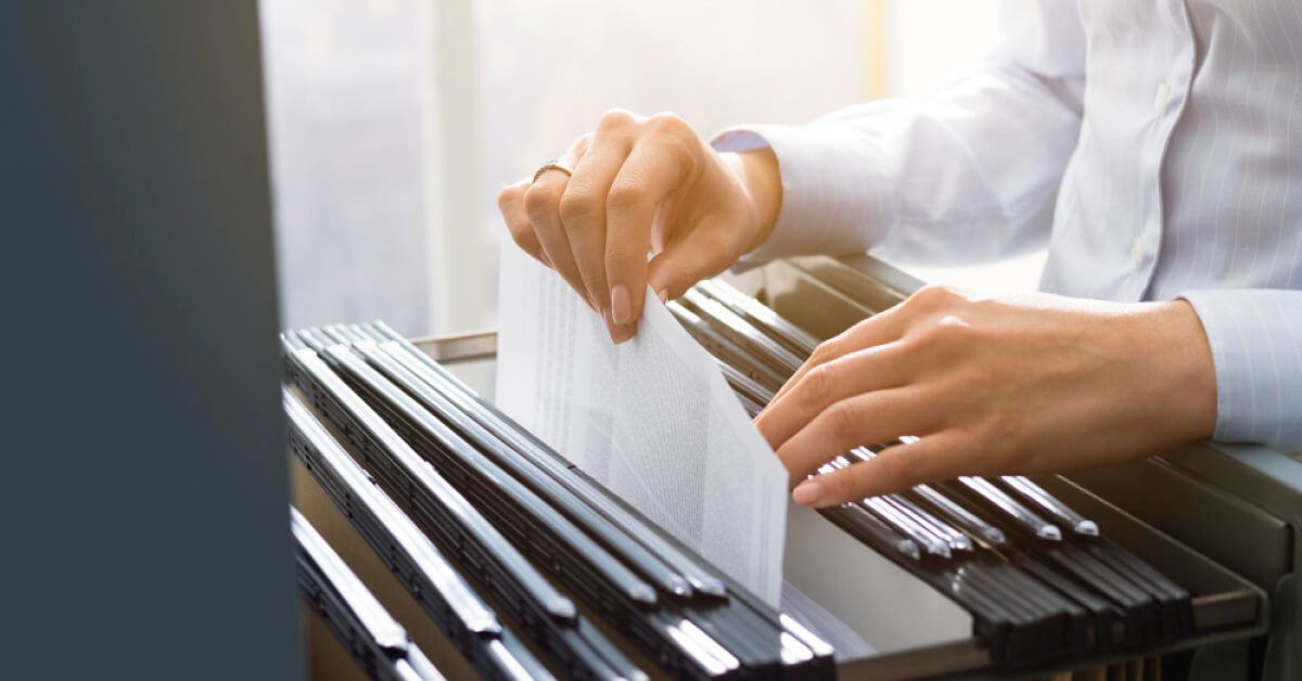 Person picking a sheet of paper out of a drawer full of files