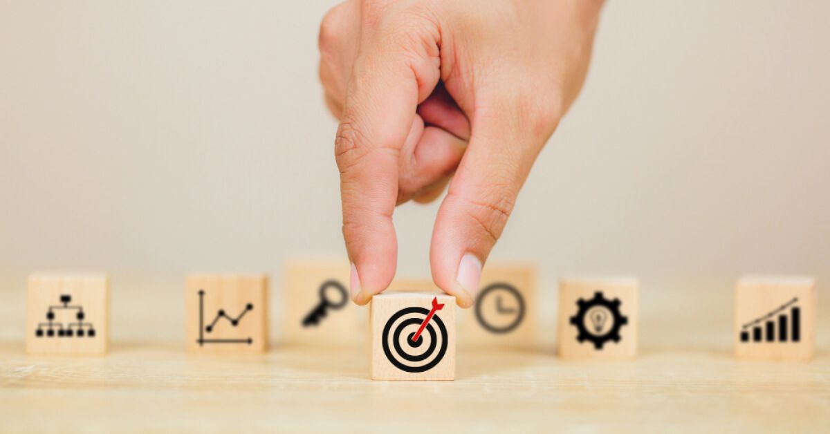Person placing a wooden block with a target graphic in front of other blocks