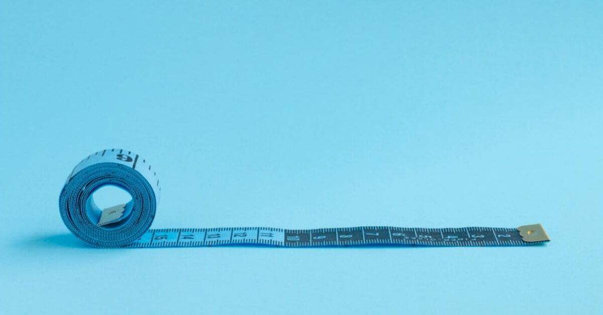 Blue measuring tape against a blue backdrop