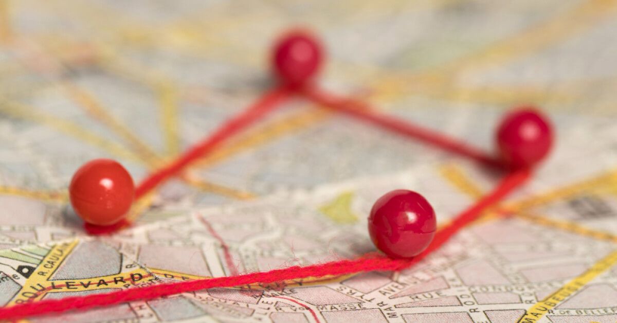 Red pins of a map connected 