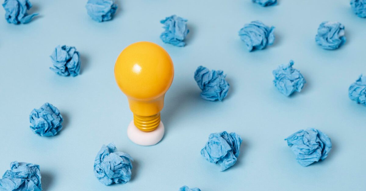 Yellow bulb amongst crushed up blue paper balls