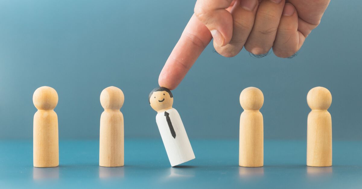 Person knocking over a wooden pawn in a series of wooden pawns