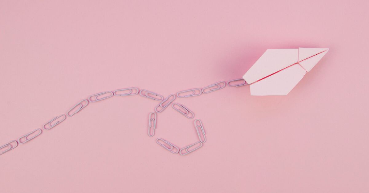 A paper plane with trailing paper clips