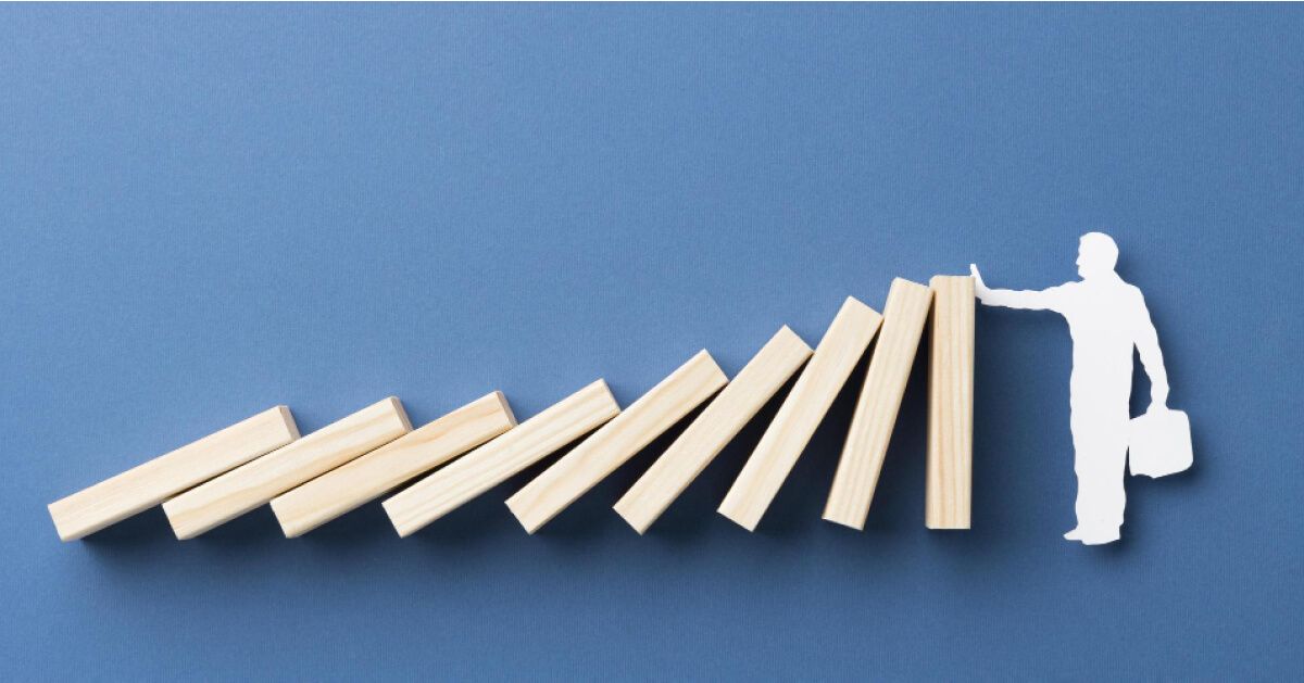 Cutout of a person stopping a series of wooden blocks from falling over