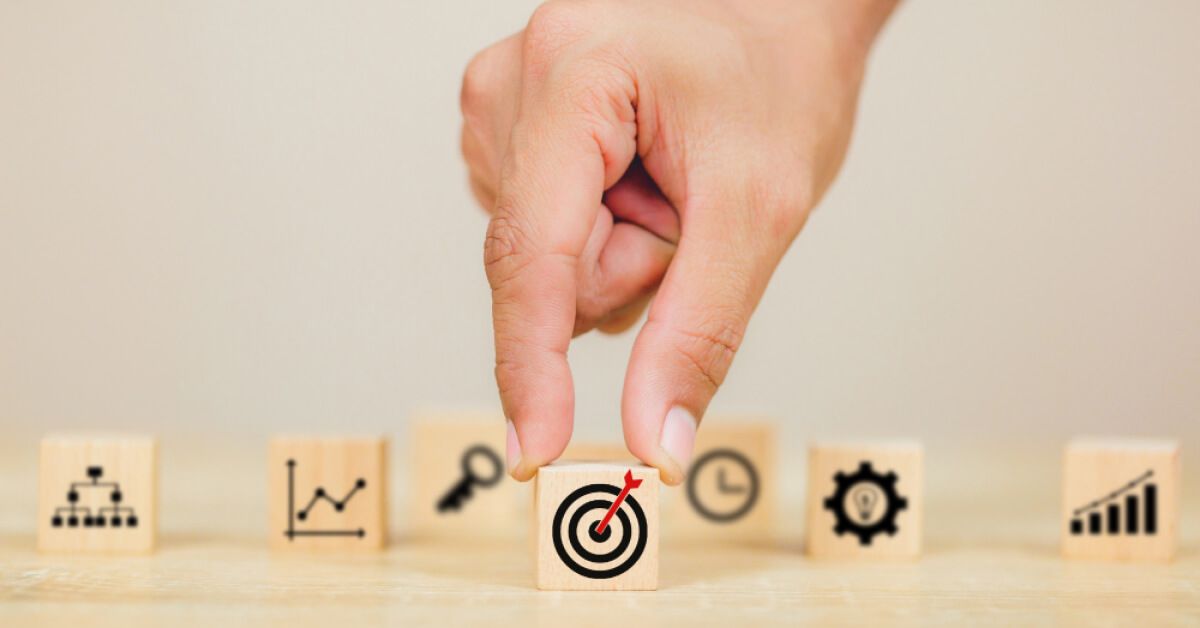 Person placing a wooden block with a target graphic in front of other blocks