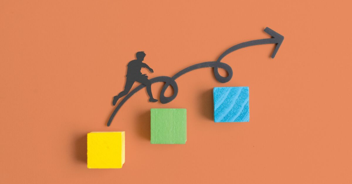 Paper cutout of a person jumping over blocks and a looping arrow
