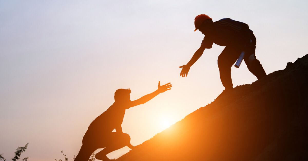 Silhouette of two people reaching out to each other