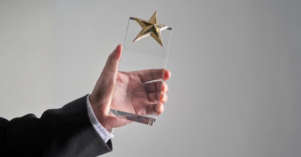 Person holding a glass award with a golden star