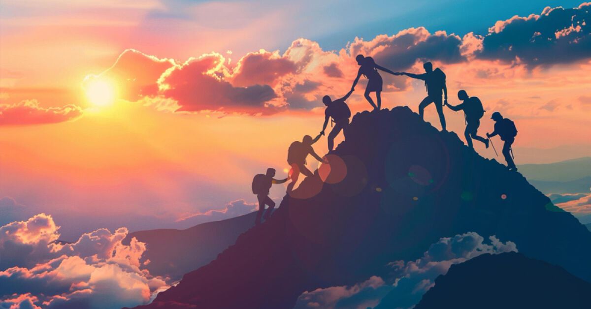 Silhouette of a group of people climbing a peak