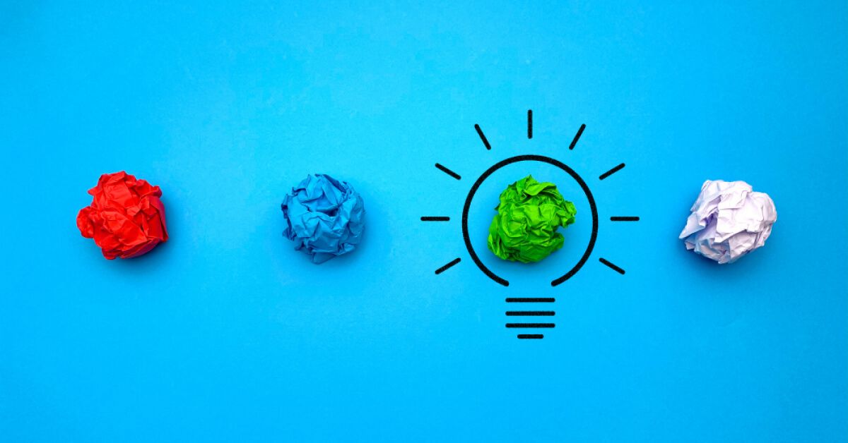 Multicoloured crushed up paper balls with a lightbulb graphic on one of them
