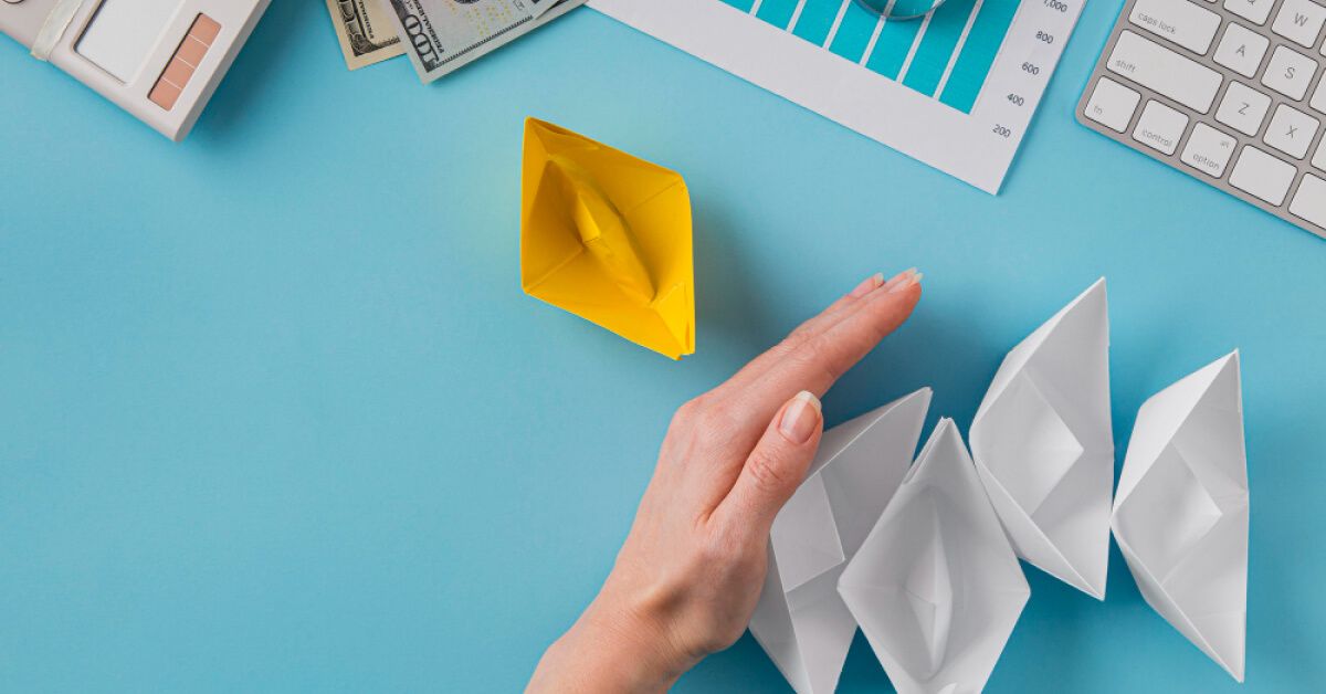 Handing choosing yellow paper boat over white paper boats