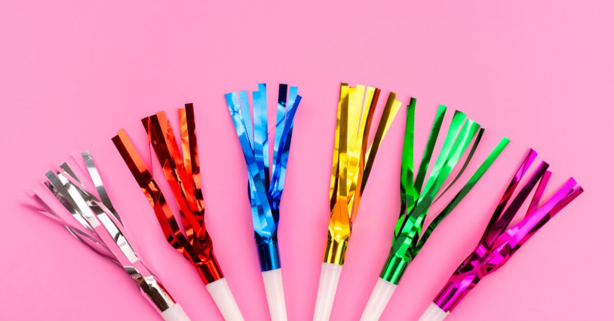 Multicoloured party poppers against a pink backdrop