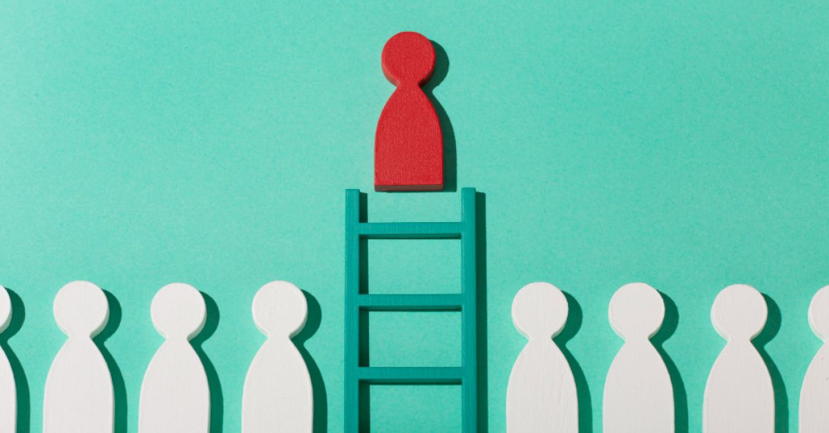 A red pawn climbing a ladder to the top while a group of other wooden pawns are underneath