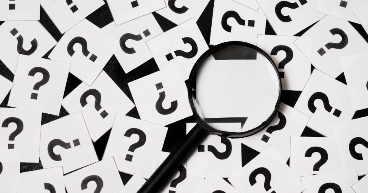 Magnifier glass over a set of cards with question marks
