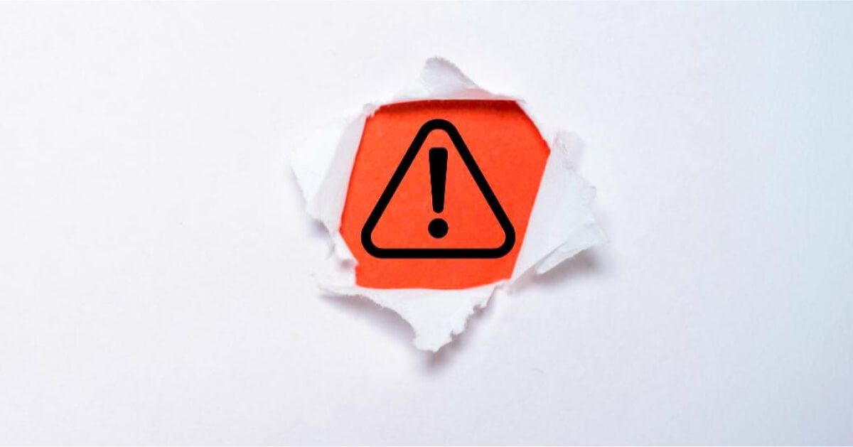 Triangular warning sign in the middle of a torn paper sheet