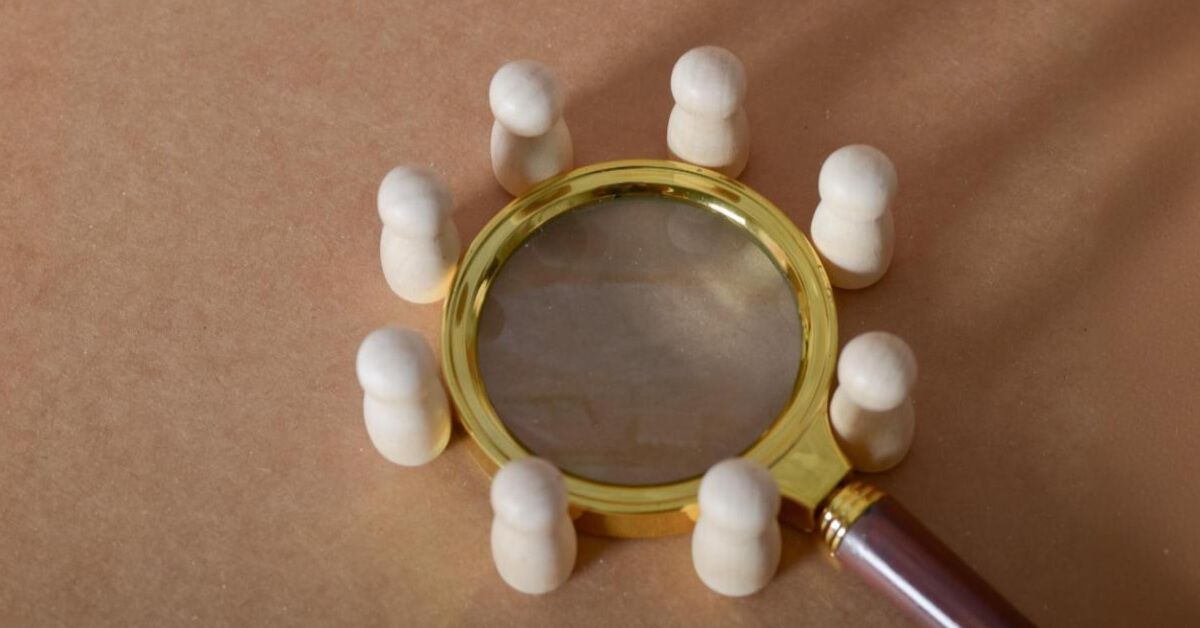 Wooden pawns around a magnifier glass