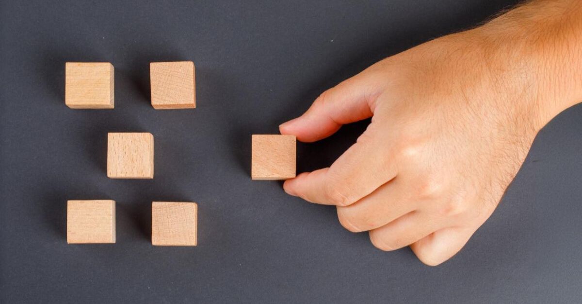 Person placing a wooden block into a grid of other wooden blocks