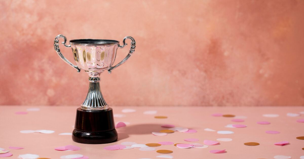 A silver trophy surrounded by pink, white and brown confetti bits