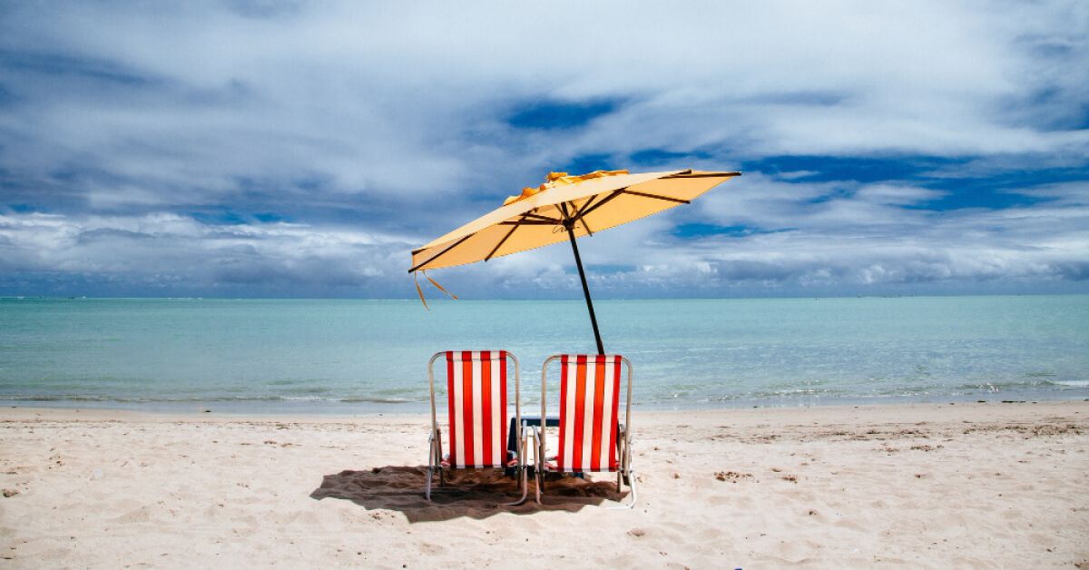 Two chairs under a shade by the beachside