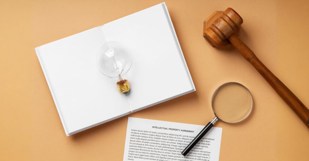 A gavel and a magnifier next to a notebook with a lightbulb