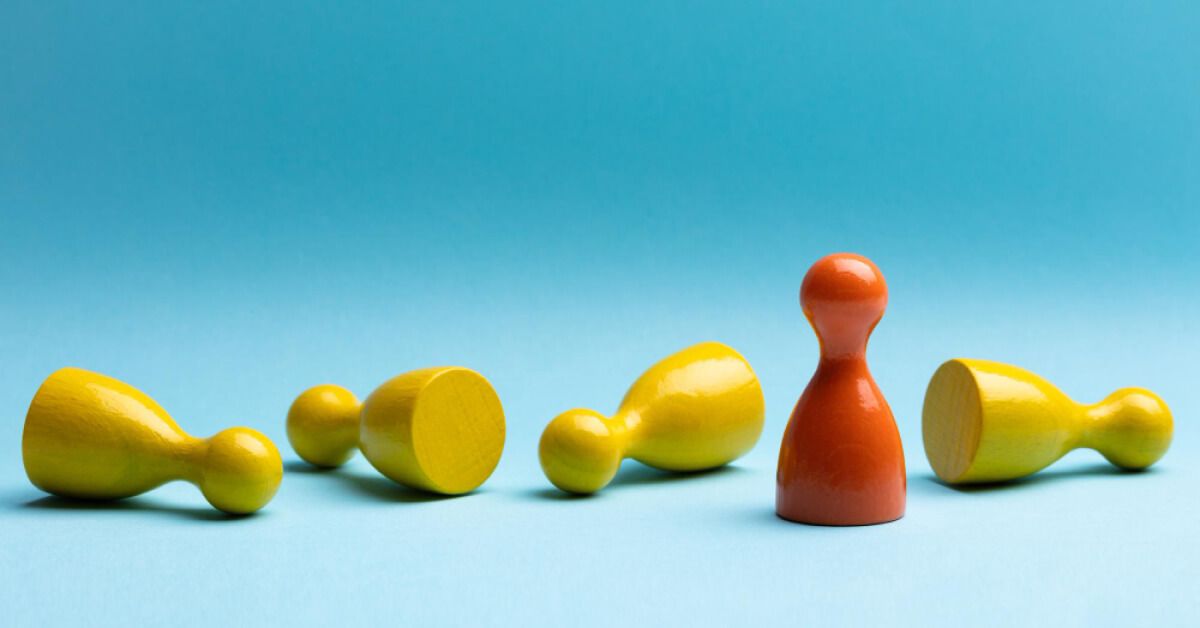 Orange pawn standing in the midst of fallen over yellow pawns