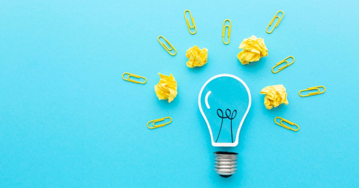 Yellow paper clips and crushed up paper balls around a vector lightbulb