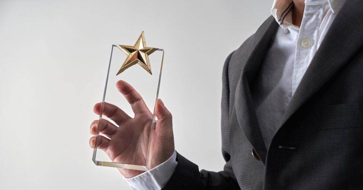 Mid section of man with formal wear holding star glass trophy