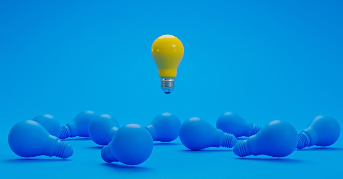 Yellow lightbulb floating over a group of blue lightbulbs