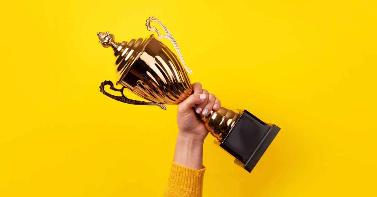 Hand of the person with a sports cup over yellow background
