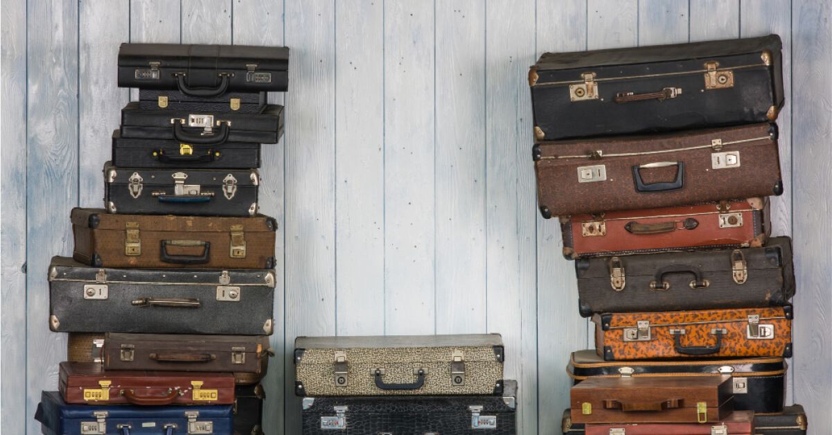 Various colours and types of luggages stacked on top of each other