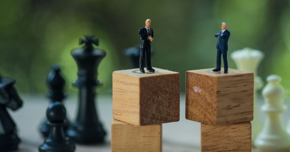 Miniature businessmen figurines in discussion over sets of wooden blocks