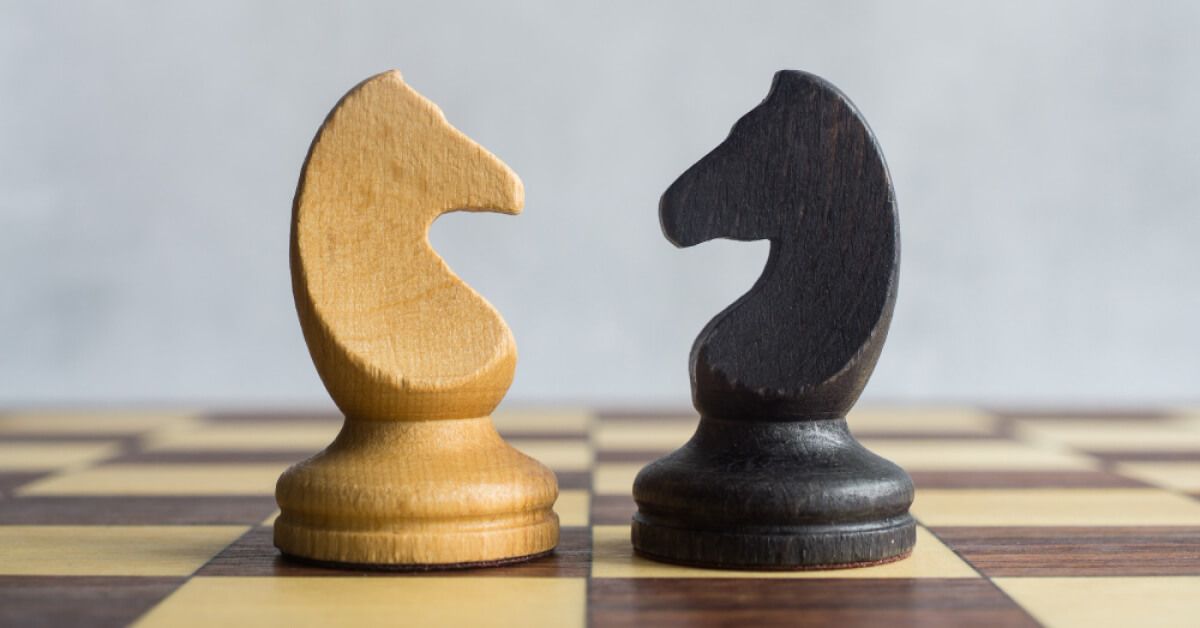 Black and white chess knight pieces facing each other