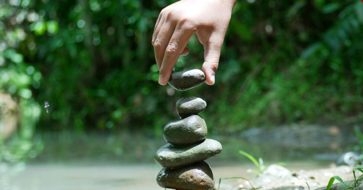 Someone stacking stones on top of another
