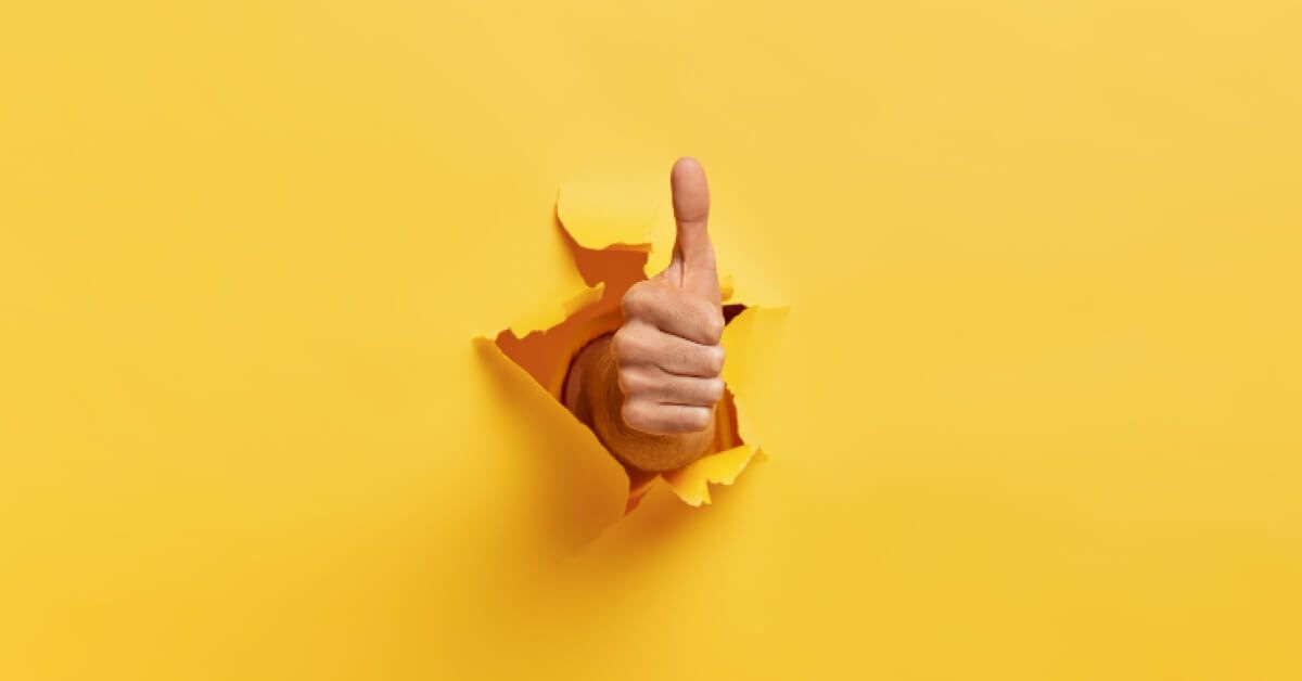 A thumbs up coming through a yellow paper wall