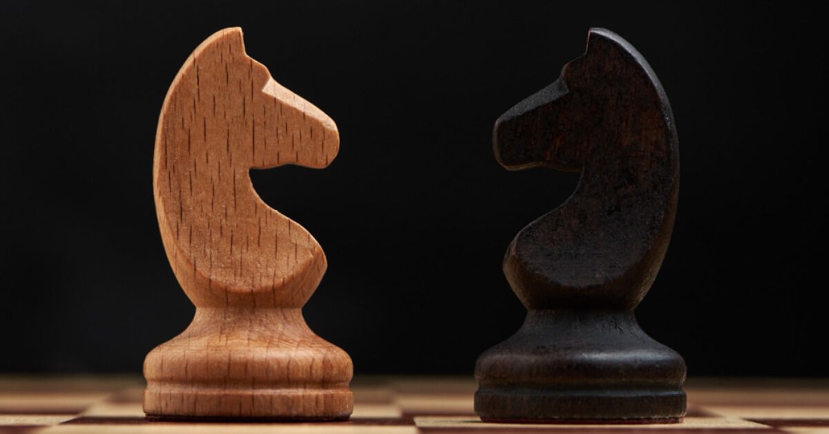 Black and white chess knight pieces facing each other