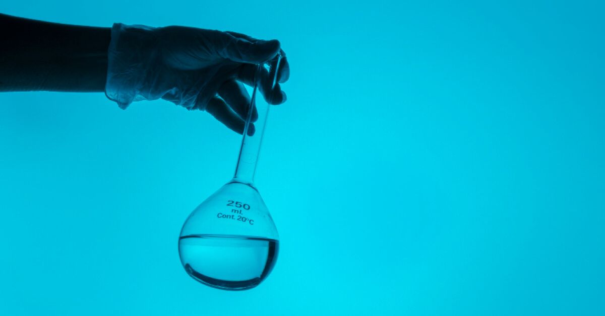 Person holding a glass lab container