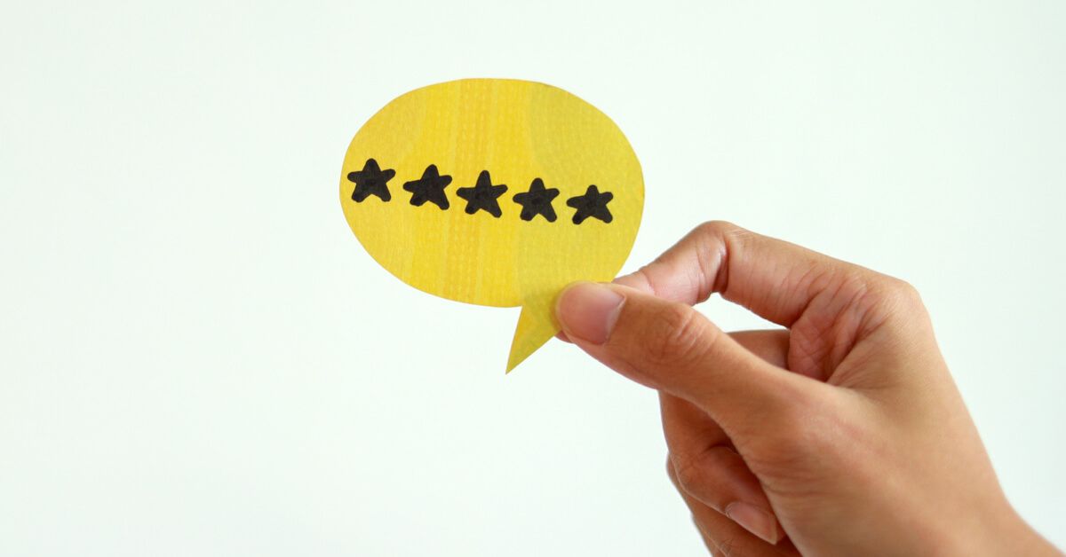 Person holding a paper cutout of a message bubble with stars on it