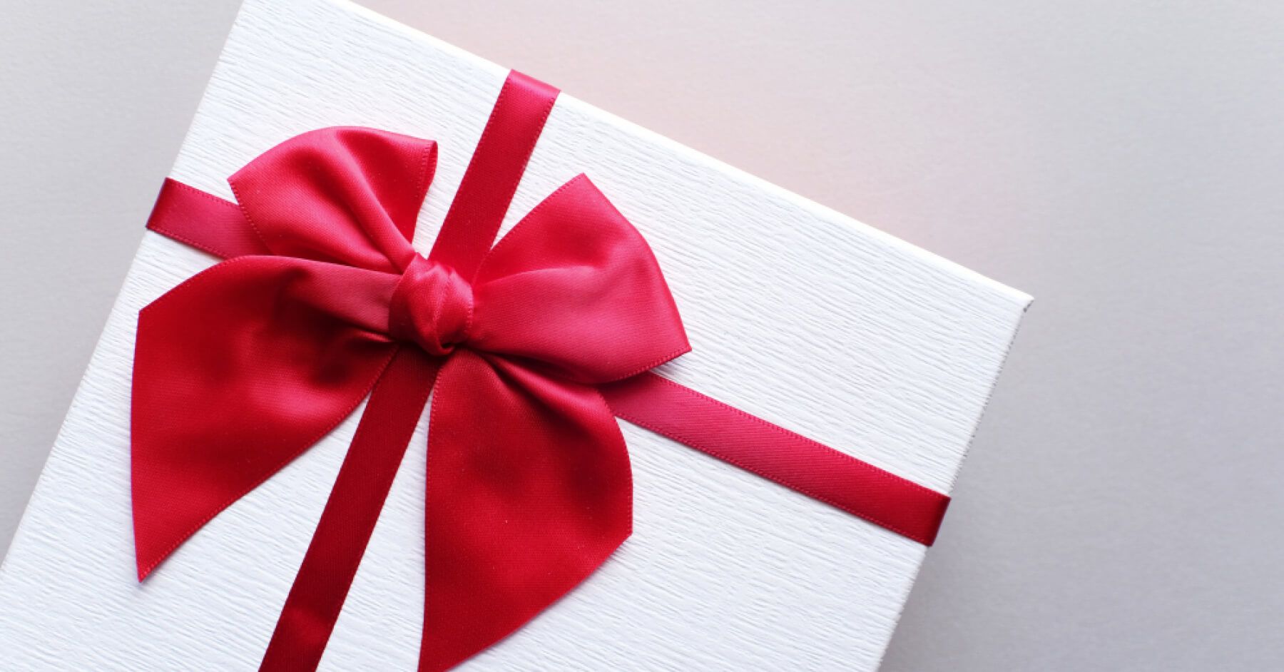 White gift box wrapped with a big red ribbon