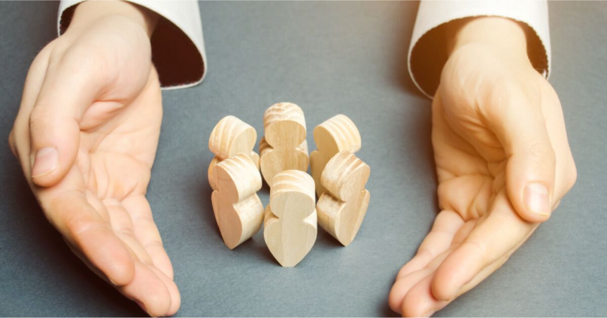 Person placing their palms around a circle of wooden pawns