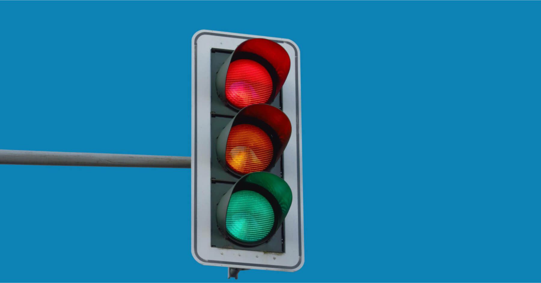 Low angle view of road signal against clear blue sky